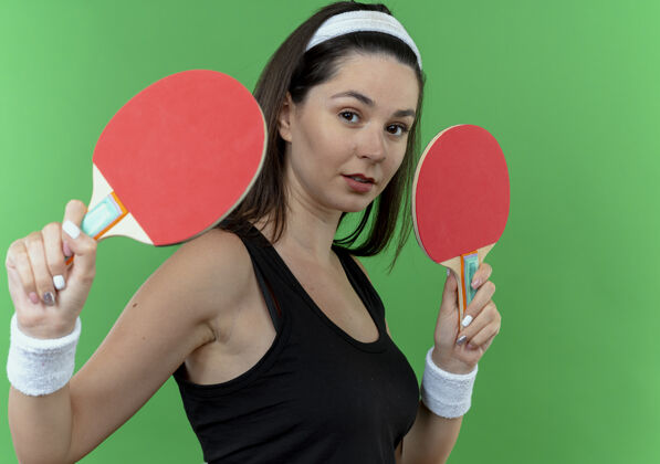 年轻戴着头巾 拿着网球拍 自信满满的年轻健身女站在绿色的墙上表情乒乓球自信