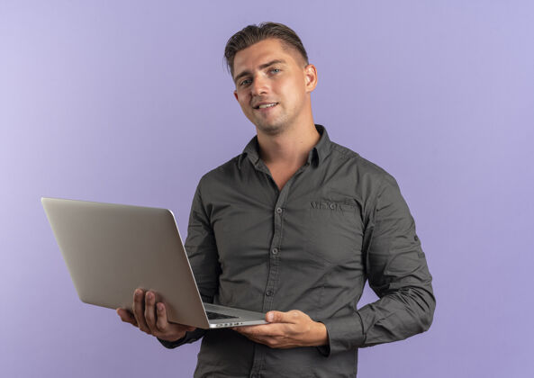 年轻年轻自信的金发帅哥拿着笔记本电脑隔离在紫罗兰色空间和复印空间英俊紫罗兰金发