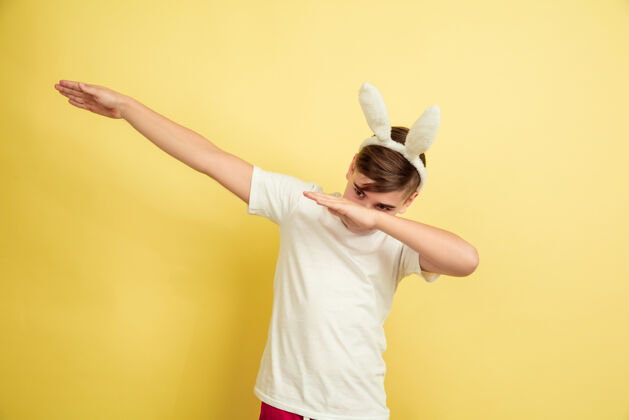耳朵男孩像复活节兔子在黄色的工作室墙上销售鸡蛋脸