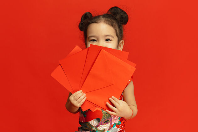欢乐穿着传统服装的亚洲可爱小女孩被隔离在红墙上年轻人节日中国