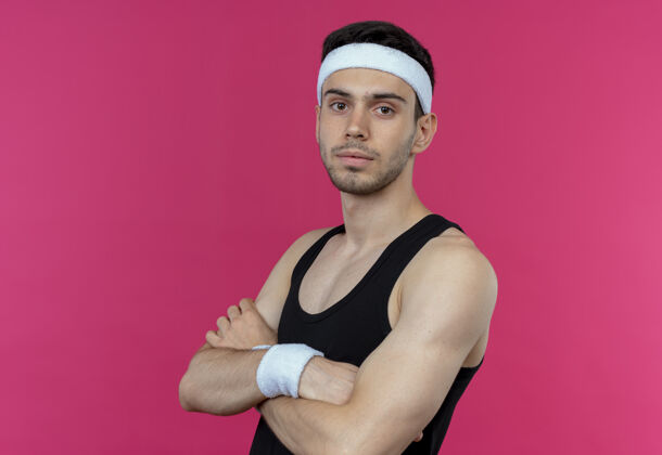胸部戴着头带的年轻运动型男子 自信严肃的表情 双臂交叉放在胸前 粉色的上方严肃运动表情