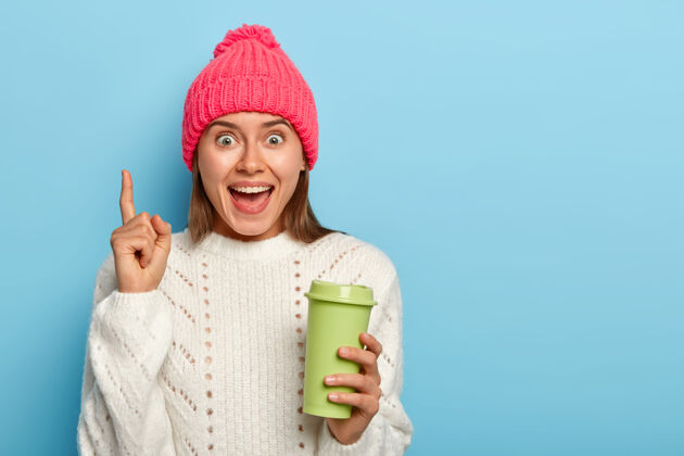 促销冬装前脸上带着快乐 咖啡杯上面带着迷人的绿色表情女人热青少年