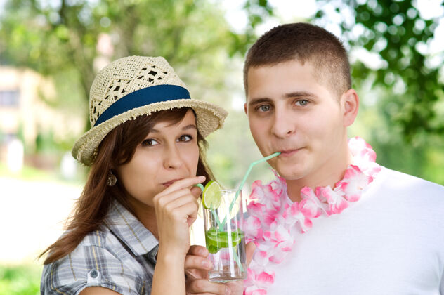 女人可爱的夫妇喝着莫吉托椰子酱花环做个鬼脸薄荷
