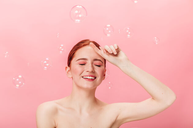 女人性感的姜女人摆出肥皂泡的姿势兴奋的裸体女孩在粉色背景上孤立地笑着手势年轻裸体