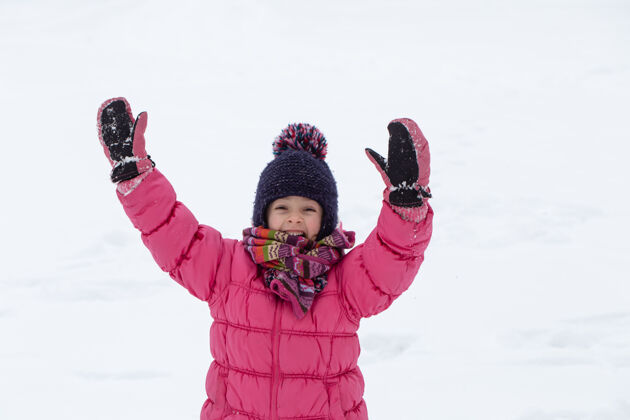 童年一个穿着粉色夹克 戴着帽子的可爱小女孩正在雪地里玩耍冬季儿童娱乐理念下雪乐趣女孩