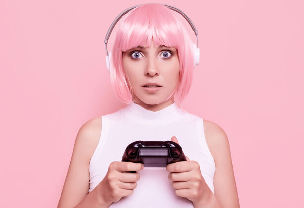 娱乐美丽快乐的游戏女孩与粉红色头发的肖像玩游戏机上五颜六色的操纵杆在工作室姿势动漫休闲
