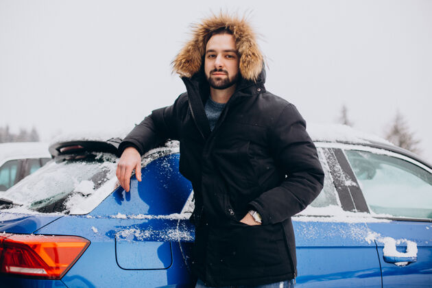 人站在被雪覆盖的汽车旁的年轻人度假旅行暴风雪