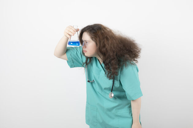 综合征穿着绿色制服的年轻女孩手里拿着一个盛着蓝色液体的玻璃罐残疾人类年轻