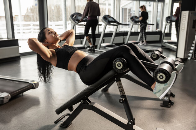 肌肉健康年轻肌肉发达的白人妇女在健身房练习器械运动女模特做腹肌锻炼 训练她的上身 腹部健康 健康的生活方式 健美强壮健身房重