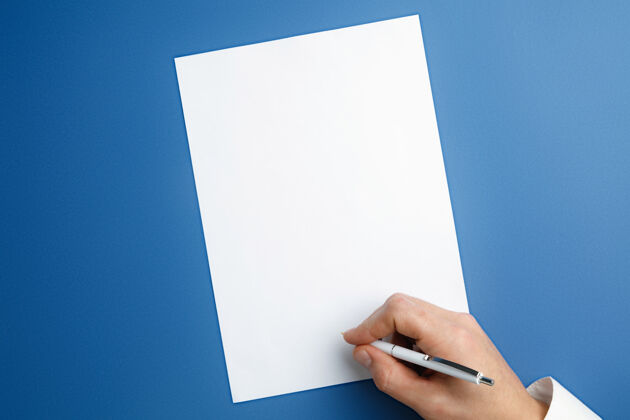拇指男性手持笔 在蓝色墙上的空白纸上书写文字或设计空白模板用于联系 广告或商业 金融 办公 采购复制空间办公室工人手臂
