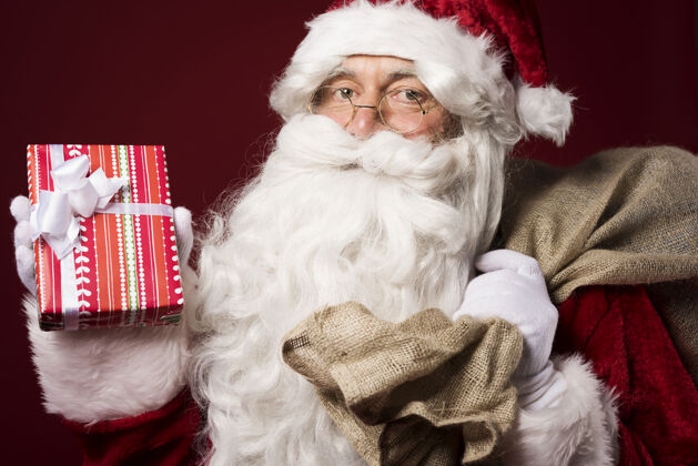 十二月圣诞老人带着一个红色背景的礼盒白人种族欢呼欢乐