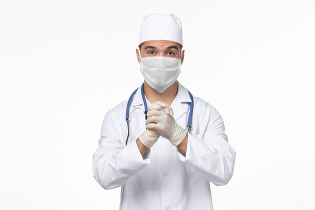 服务正面图：男医生穿着医疗服 戴着防冠状病毒口罩 白色办公桌上病毒冠状病毒-疾病大流行男性疾病视图