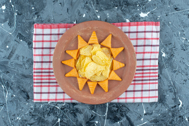 奶酪奶酪片和圆锥形片放在盘子里 茶毛巾放在大理石上堆奶酪薯条盐