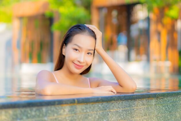 女性肖像美丽的亚洲年轻女子放松微笑享受休闲酒店度假村游泳池周围水户外休闲