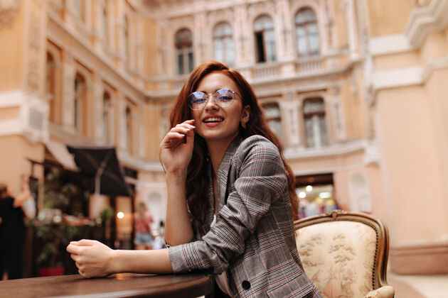 城市穿着格子装戴着眼镜的漂亮女人坐在城市咖啡馆里健康女性眼镜
