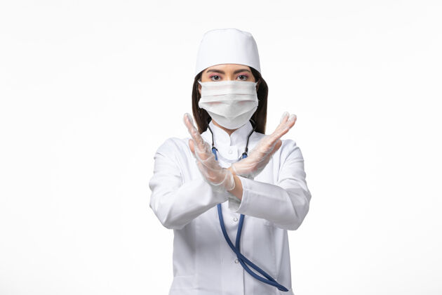 病毒正面图：女医生穿着白色无菌医疗服 带口罩 因柯维德-白墙疾病显示禁止标志柯维德-大流行病毒疾病到期医疗正面