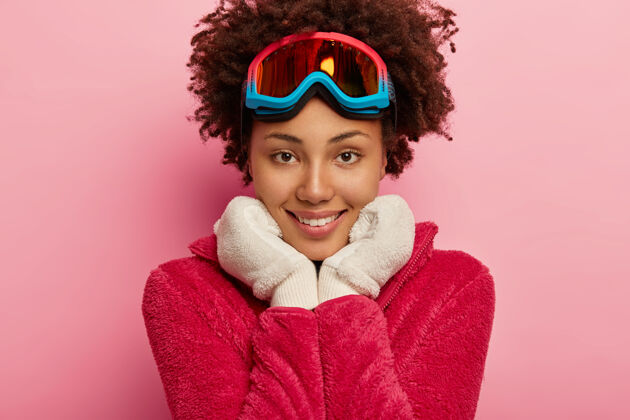 满意特写镜头：一个戴着滑雪板面具 双手放在下巴下 戴着温暖的白手套 直视镜头的帅哥牙关装备高兴