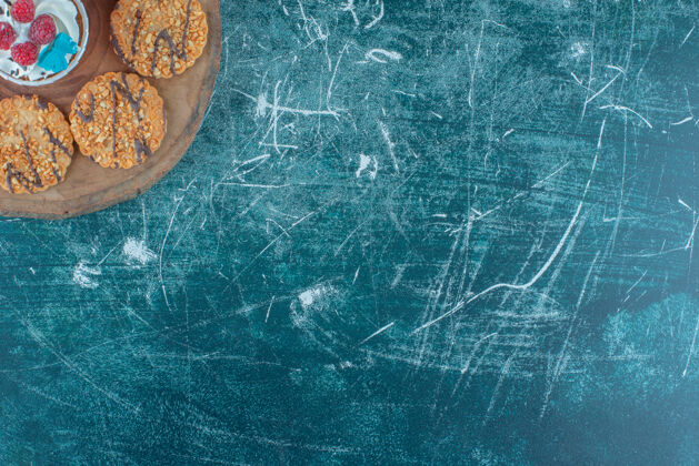 纸杯蛋糕在蓝色背景的木板上 饼干围绕着一个纸杯蛋糕高质量的照片曲奇美味甜点