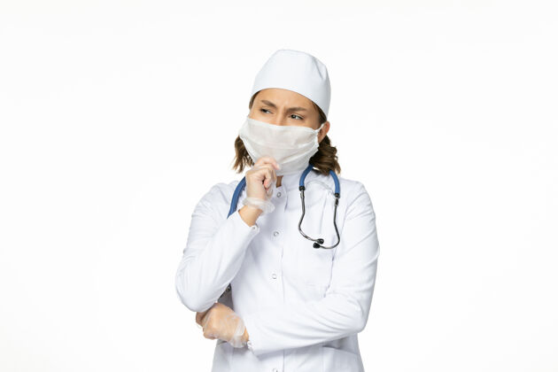 医生正面图年轻女医生戴着无菌口罩和手套因冠状病毒深入思考白色表面手套前口罩