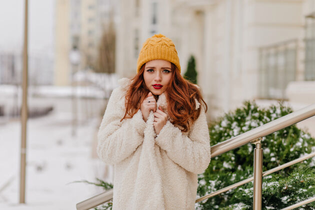 积极快乐的女孩戴着可爱的黄色帽子享受冬天有兴趣的女士在户外度过十二月的一天黑发冬天灵感