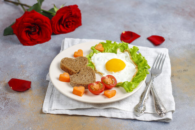 餐桌情人节早餐-炸鸡蛋 心形面包和新鲜蔬菜菜肴健康面包