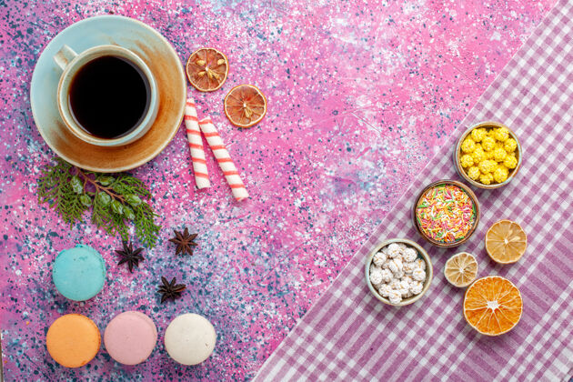 麦卡龙顶视图甜美的糖果五颜六色的知己与茶和马卡龙在粉红色的办公桌上五颜六色糖果茶