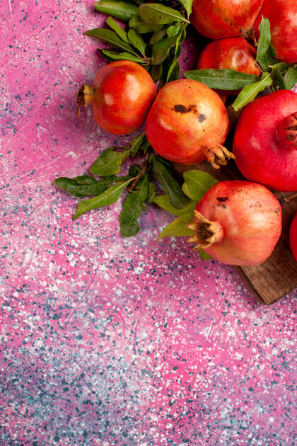 水果粉红色书桌上有新鲜的红石榴和绿叶顶部可食用的水果生的