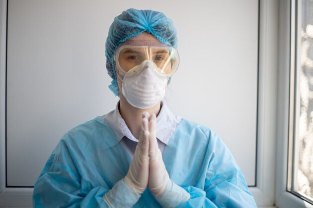 流行病一名身穿医护人员防护装备的女性拍摄 并祈祷生物学医生面罩