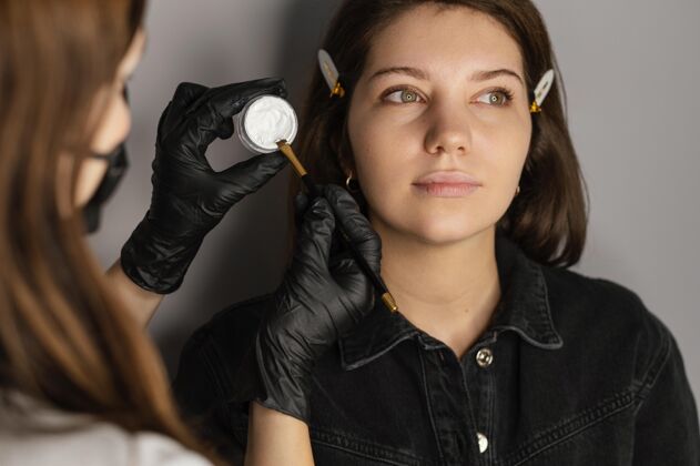 头发从专家那里得到眉毛治疗的女人的正视图手术美容刷子
