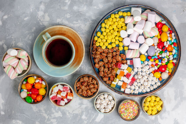 糖果顶视图糖果组成不同颜色的糖果与棉花糖和一杯茶在白色的办公桌上糖果邦邦甜的壁橱杯子桌子茶