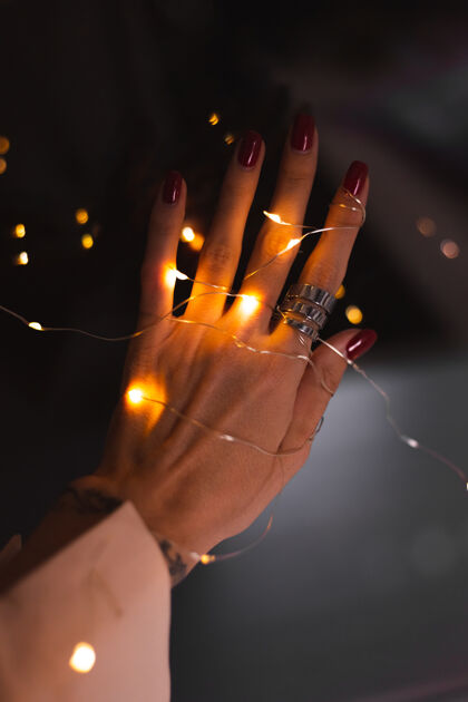 女性美丽的黑色照片的妇女手指头与大银戒指上的花朵和发光的灯光迷人富有时尚