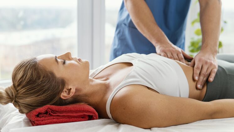 健康男性骨科治疗师检查女性患者腹部的正视图运动病人治疗师