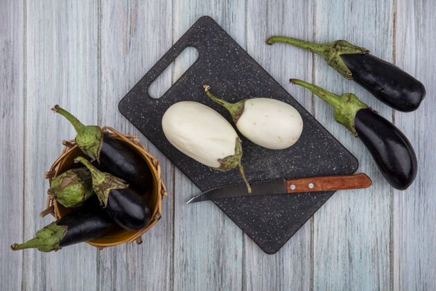 白切菜板上的白色茄子和刀的俯视图 篮子和木制背景上的黑色纳迪亚茄子茄子黑刀