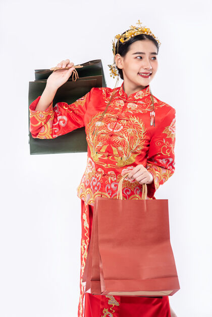 成人穿旗袍西服的女人微笑着从中国新年购物纸袋面具购物旗袍