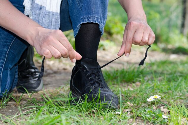 时尚特写镜头一个男人的手绑鞋带在草地覆盖的领域扭运动鞋男