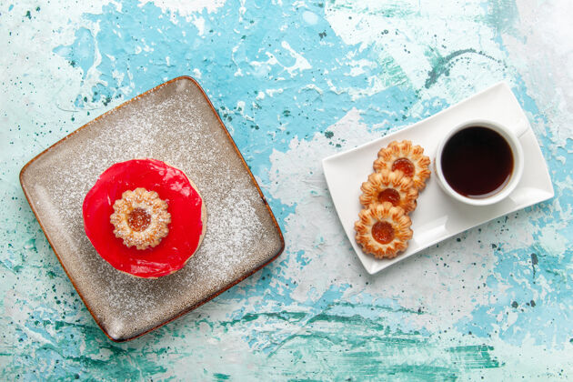 早餐俯瞰图红色奶油蛋糕和浅蓝色背景饼干蛋糕饼干甜甜的糖派茶顶部热的杯子