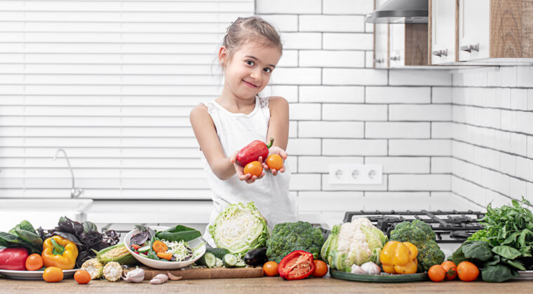 微笑一个可爱的小女孩拿着新鲜的蔬菜 一边准备一份沙拉女孩健康产品