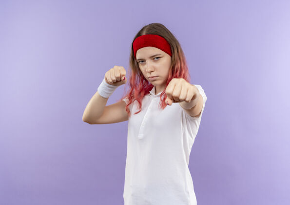 运动年轻的运动女孩站在紫色的墙上 摆出一副拳击手的姿势拳击手市民喜欢
