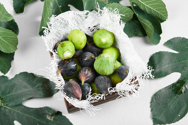 蔬菜绿色和紫色的无花果放在毛巾上的木托盘里热带食品质量
