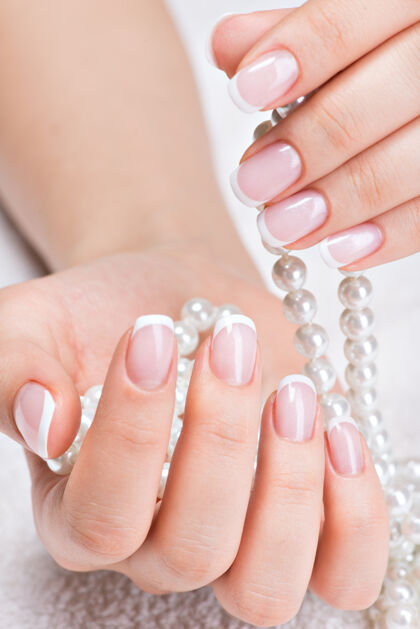 珍珠美丽的女人的指甲和美丽的法国美甲和白珍珠治疗女士美甲
