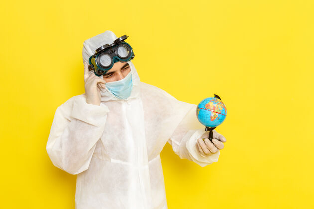 封面正面图：一个穿着特殊衣服的男科学工作者 手里拿着小地球仪 在黄色的桌子上思考工人手持套装