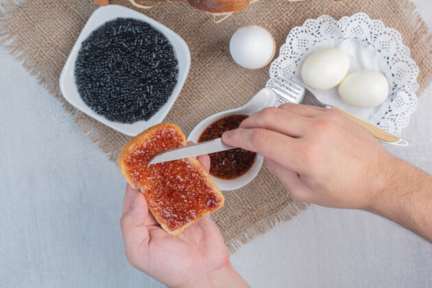 鸡蛋手用刀在面包上抹果酱好吃的果酱麻布