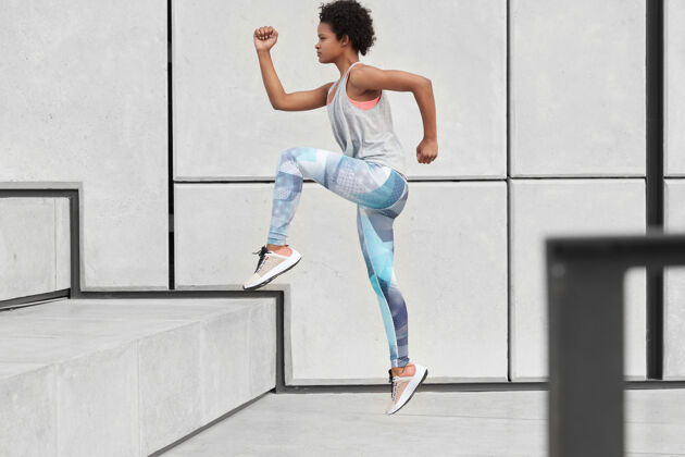 紧身裤健康健康的女人跑上楼梯 穿着舒适的衣服和运动鞋 慢跑锻炼 在城市环境中做运动 速度快 侧摆姿势健康和决心的概念女人休息挑战