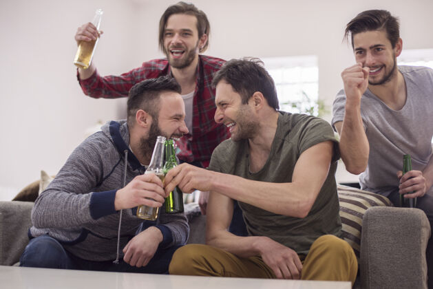 尖叫朋友们喝啤酒看足球赛电视啤酒瓶微笑