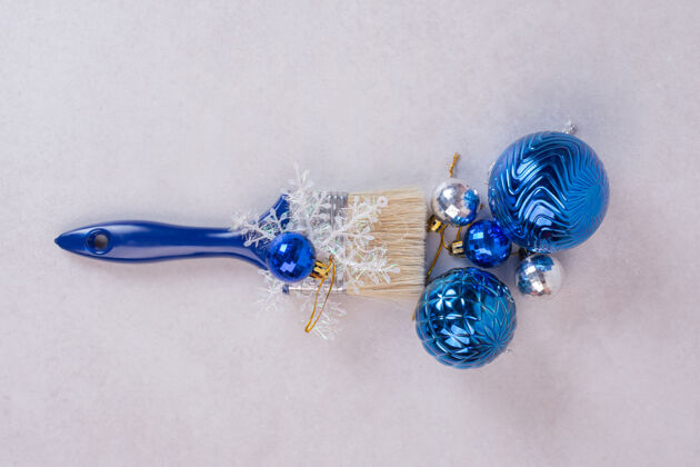 雪花白色表面上有圣诞球的蓝色刷子蓝色画笔装饰品