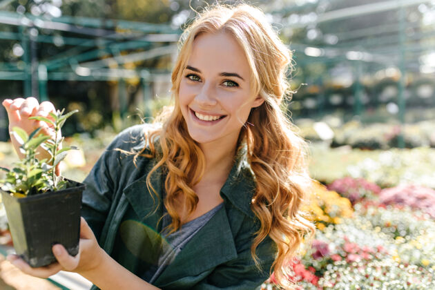玫瑰一位金发碧眼 笑容温柔的年轻女子 身着绿色长袍 系着腰带 正在温室里工作女人花园自然