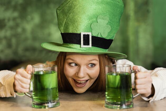 派对笑脸女人用饮料庆祝圣帕特里克节三叶草绿色帽子