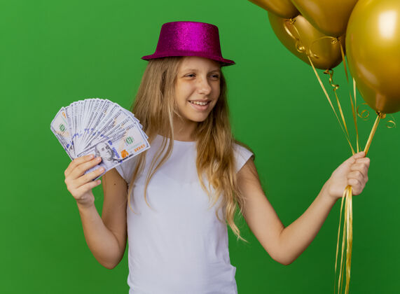 气球戴着节日帽子拿着钱的漂亮小女孩女孩聚会节日
