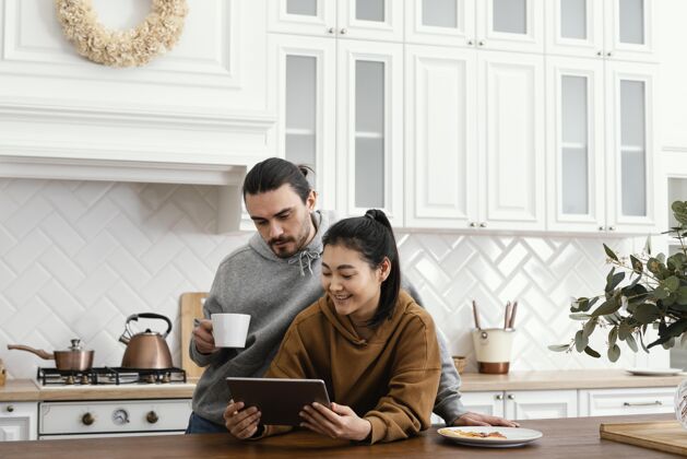 科技一对夫妇在厨房吃早餐 并使用平板电脑休闲一起室内