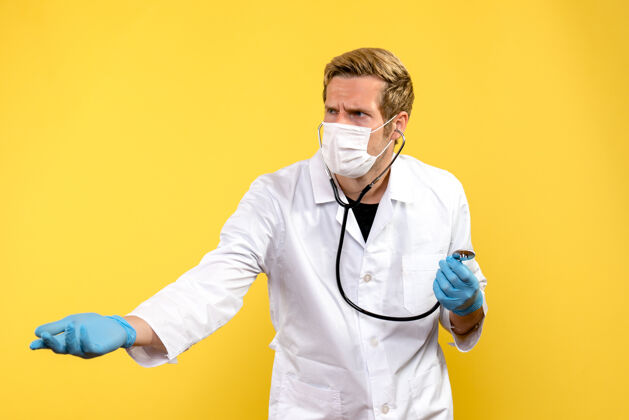 病毒正面图男医生戴着无菌口罩 背景上是黄色大流行病毒冠状病毒外套男性医生正面